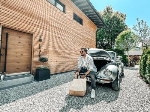 a man is sitting on the hood of a car at ZSAM Chalets mit Sauna und Hottub in Garmisch-Partenkirchen