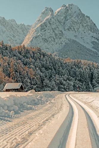 a snow covered road with a mountain in the background at ZSAM Chalets mit Sauna und Hottub in Garmisch-Partenkirchen