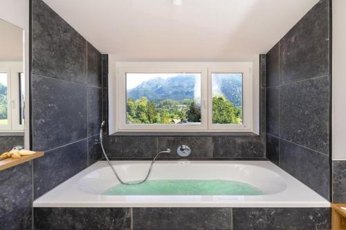 un bagno con vasca e 2 finestre di Ferienwohnungen Friedenshöhe in Oberammergau a Oberammergau