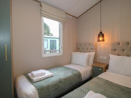 two beds in a small room with a window at Owl in Leominster