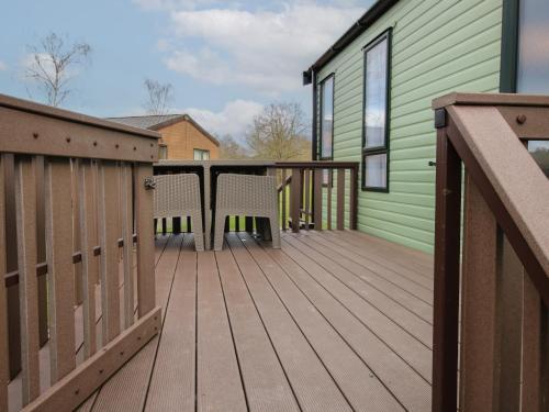 a deck with two chairs and a green house at Owl in Leominster