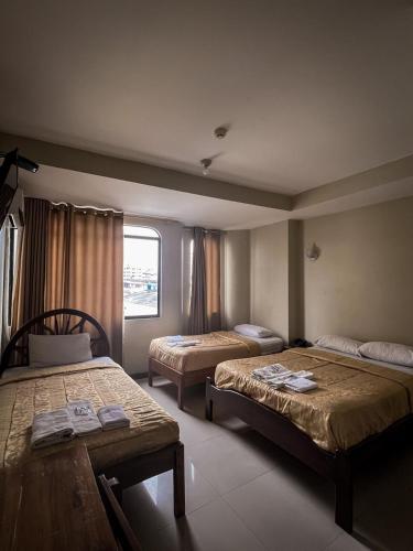 a hotel room with two beds and a window at Hostal Wilson Inn in Guayaquil