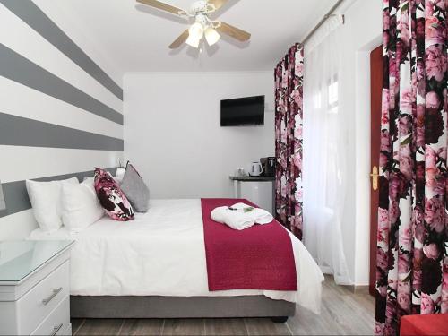 a small bedroom with a bed with a red blanket at Glennies Guesthouse in Somerset West