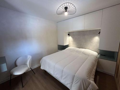 une chambre avec un lit blanc et une chaise dans l'établissement Appartement rénové 2 pièces cabine avec balcon et accès piscine - Méribel - FR-1-180-637, à Les Allues