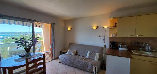 Il dispose d'une cuisine et d'un salon avec un canapé et une table. dans l'établissement LE CAPITOLE Vue mer Studio cabine 27m2 les pieds dans leau 2 adultes 2 enfants clim et garage, à Fréjus