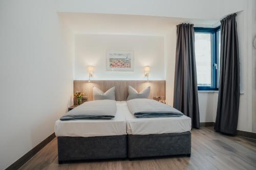 a bedroom with a large bed with two pillows at Lechpark Hotel in Untermeitingen