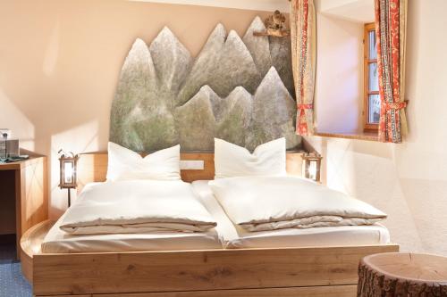 1 dormitorio con 1 cama con una pintura en la pared en Gasthof Falkenstein - Metzgerei Schwaiger -, en Flintsbach