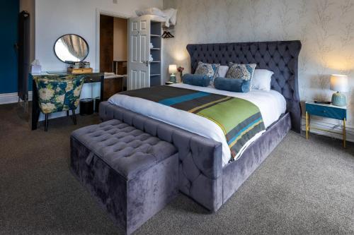 a bedroom with a large bed with a tufted headboard and a desk at The Royal Station Hotel in Carnforth