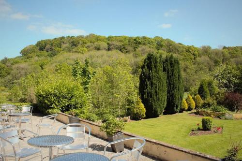 a patio with tables and chairs in a garden at The Paddocks Hotel in Symonds Yat