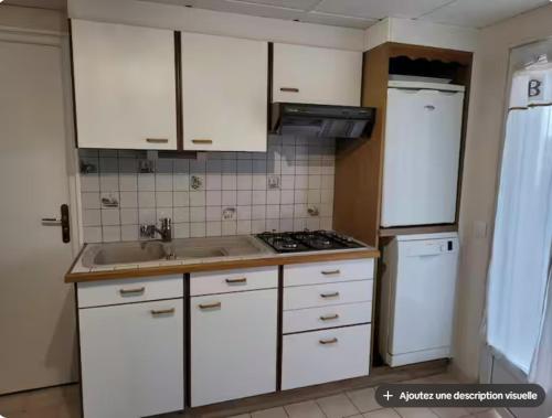 a kitchen with white cabinets and a sink and a stove at Charmant appartement 35 m2 avec terrasse et jardin in Domont