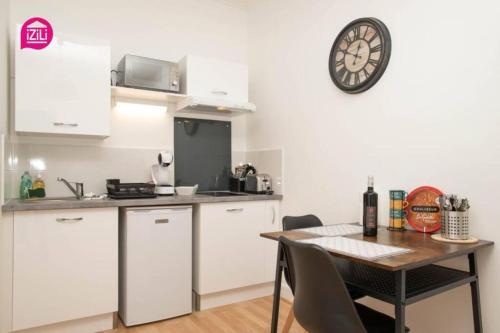une cuisine avec une table et une horloge au mur dans l'établissement Huka Studio - Centre Ville Poitiers, à Poitiers