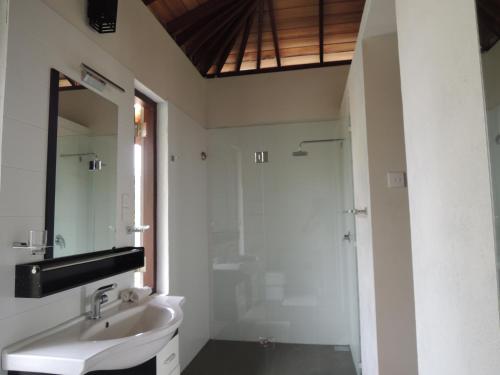 a white bathroom with a sink and a shower at The Residence Bentota in Bentota