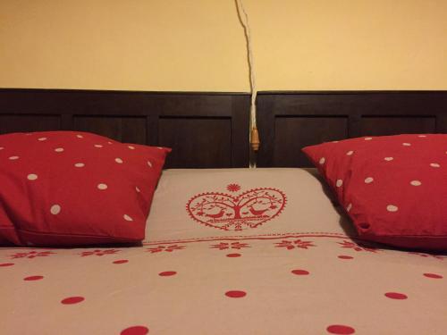 a bed with two red pillows and a heart pillow at Casa Coll in Barruera