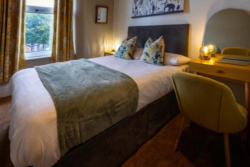 a bedroom with a bed with a desk and a chair at The Royal Station Hotel in Carnforth