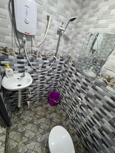a bathroom with a toilet and a sink at Wika Homestay in Lunas