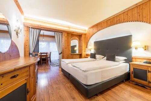 a bedroom with a large bed and a table at Croce Bianca Leisure & Spa Hotel in Canazei