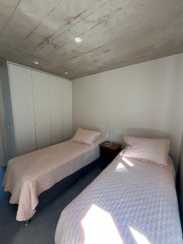 two beds in a room with white walls at SANTAMARIADELMAR Casa a estrenar frente al mar in Manantiales