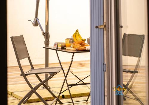 une table avec une chaise et une table avec des bananes et du pain dans l'établissement Au soleil levant*terrasse*Local à vélo*oc keys, à Castelnaudary