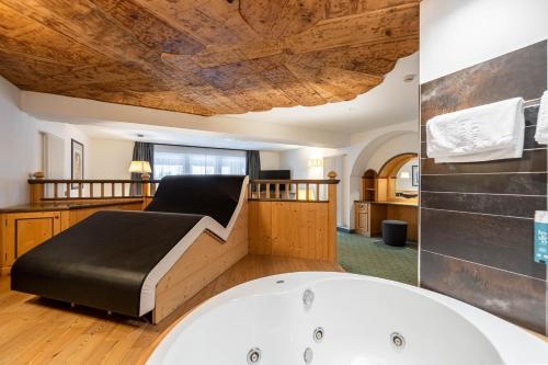 łazienka z wanną i łóżko w pokoju w obiekcie Croce Bianca Leisure & Spa Hotel w mieście Canazei