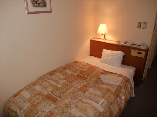 a bedroom with a bed in a hotel room at Hotel Sunroute Goshogawara in Goshogawara