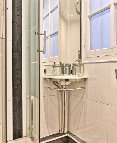 une salle de bain avec une douche avec un lavabo et un miroir dans l'établissement Pleasant Apartment Close to Galerie Lafayette - II, à Paris