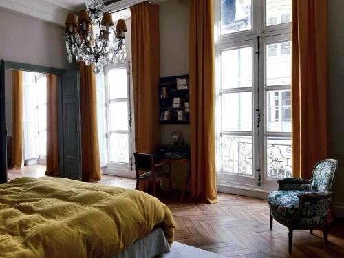 - une chambre avec un lit, un lustre et des fenêtres dans l'établissement Apartment Carrelet de Loisy, à Dijon