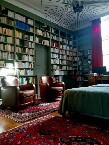 une bibliothèque avec deux chaises, un lit et des étagères dans l'établissement Apartment Carrelet de Loisy, à Dijon
