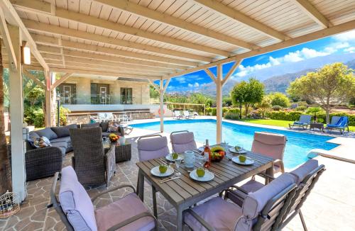 a patio with a table and chairs and a pool at Mirsini Villa Privater Pool Jacuzzi in Georgioupolis