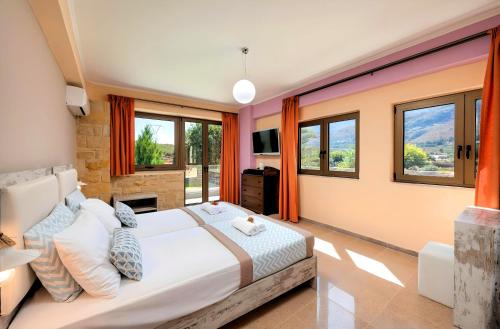 a bedroom with a large bed and windows at Mirsini Villa Privater Pool Jacuzzi in Georgioupolis