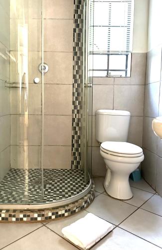 a bathroom with a toilet and a glass shower at Pass-through Apartments in Pretoria
