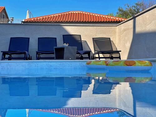 a pool with chairs and a table next to a wall at Apartment Bonum with Private Pool in Šilo