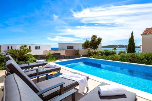 a swimming pool with chaise lounge chairs next to a swimming pool at Luxuriöse Villa Dolce Vita Direkt Am Meer Mit Privatem Pool Und Parkplatz in Sevid