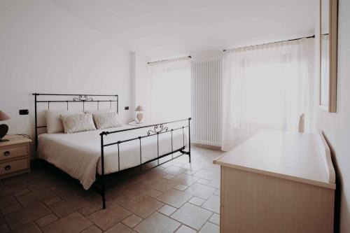 a white bedroom with a bed and a table at Residence Rose di Fratta in Cupramontana