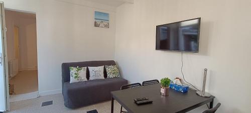 - un salon avec une chaise, une table et une télévision dans l'établissement La Pivoine, à Trouville-sur-Mer