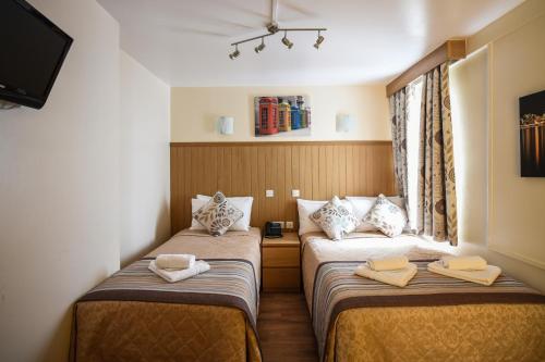 two twin beds in a room with a window at Linden House Hotel in London