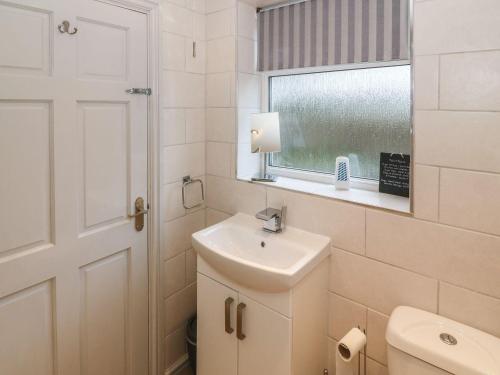 a bathroom with a sink and a toilet and a window at Camwy in Llanfairpwllgwyngyll