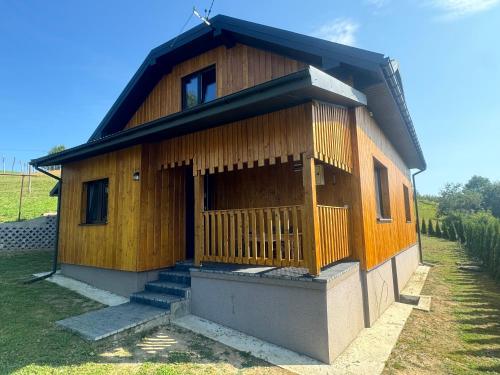 a small wooden house with a porch and stairs at Jelonkowe Wzgórze in Desznica