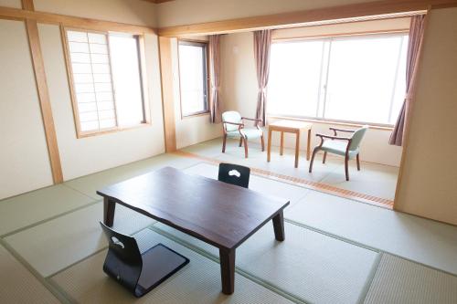 a living room with a wooden table and chairs at Seaside Hotel Taimaru Kaigetsu in Naruto