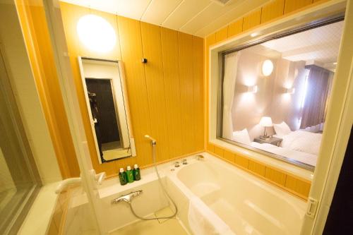 a bathroom with a tub and a large window at Seaside Hotel Taimaru Kaigetsu in Naruto
