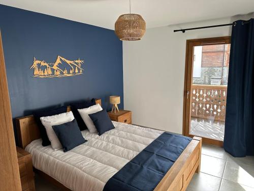 une chambre avec un grand lit avec un mur bleu dans l'établissement Appartement neuf tout confort super emplacement, à Samoëns