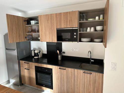 une cuisine avec un évier et un micro-ondes dans l'établissement Appartement neuf tout confort super emplacement, à Samoëns