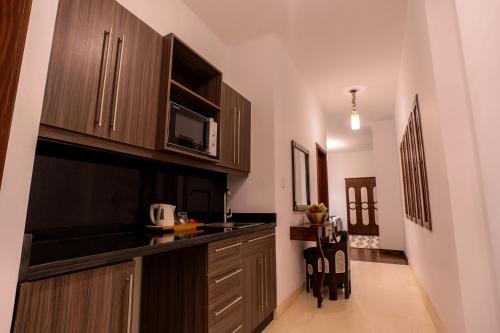 a kitchen with wooden cabinets and a counter top at Villa Mango Hotel, near the American University in Cairo, AUC, New Cairo in Cairo