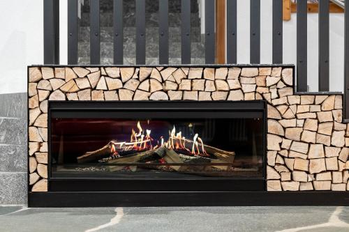 a stone fireplace with a fire in it at Croce Bianca Leisure & Spa Hotel in Canazei