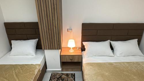 a bedroom with two beds and a lamp on a night stand at Bisan Apartment in Madinat Al Ashir min Ramadan