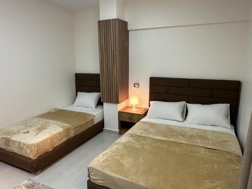 a bedroom with two beds and a table with a lamp at Bisan Apartment in Madinat Al Ashir min Ramadan