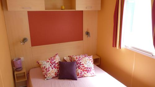 Cette petite chambre comprend un lit avec des oreillers. dans l'établissement Camping Sable d'Or 3 chambres, au Cap d'Agde