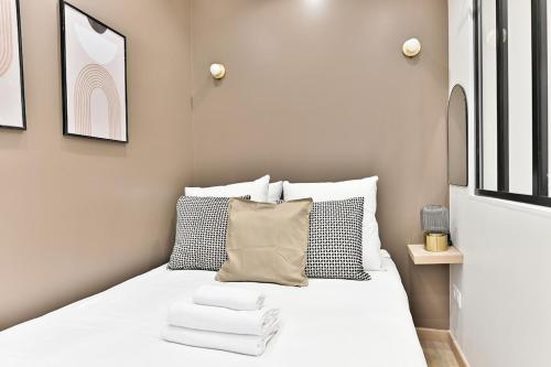 une chambre avec un lit avec des draps blancs et des oreillers dans l'établissement Central equipped apartment Paris Nation - II, à Paris