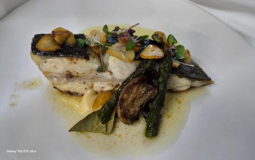 a white plate of food with meat and asparagus at Fonda Ca la Manyana in Sant Juliá de Vilatorta