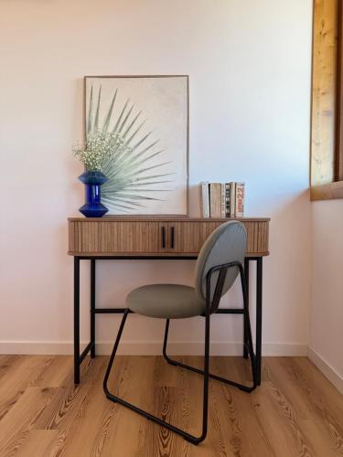 a desk with a chair and a vase on it at Costa Brava Alojamento in Benedita