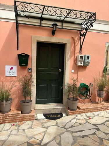 a green door on a pink building with potted plants at Vilia Port House- Corfu Centre in Mantoúkion